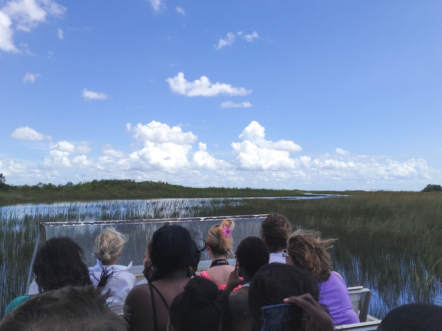 Passengers aboard an airboat crossing open water in the Florida Everglades