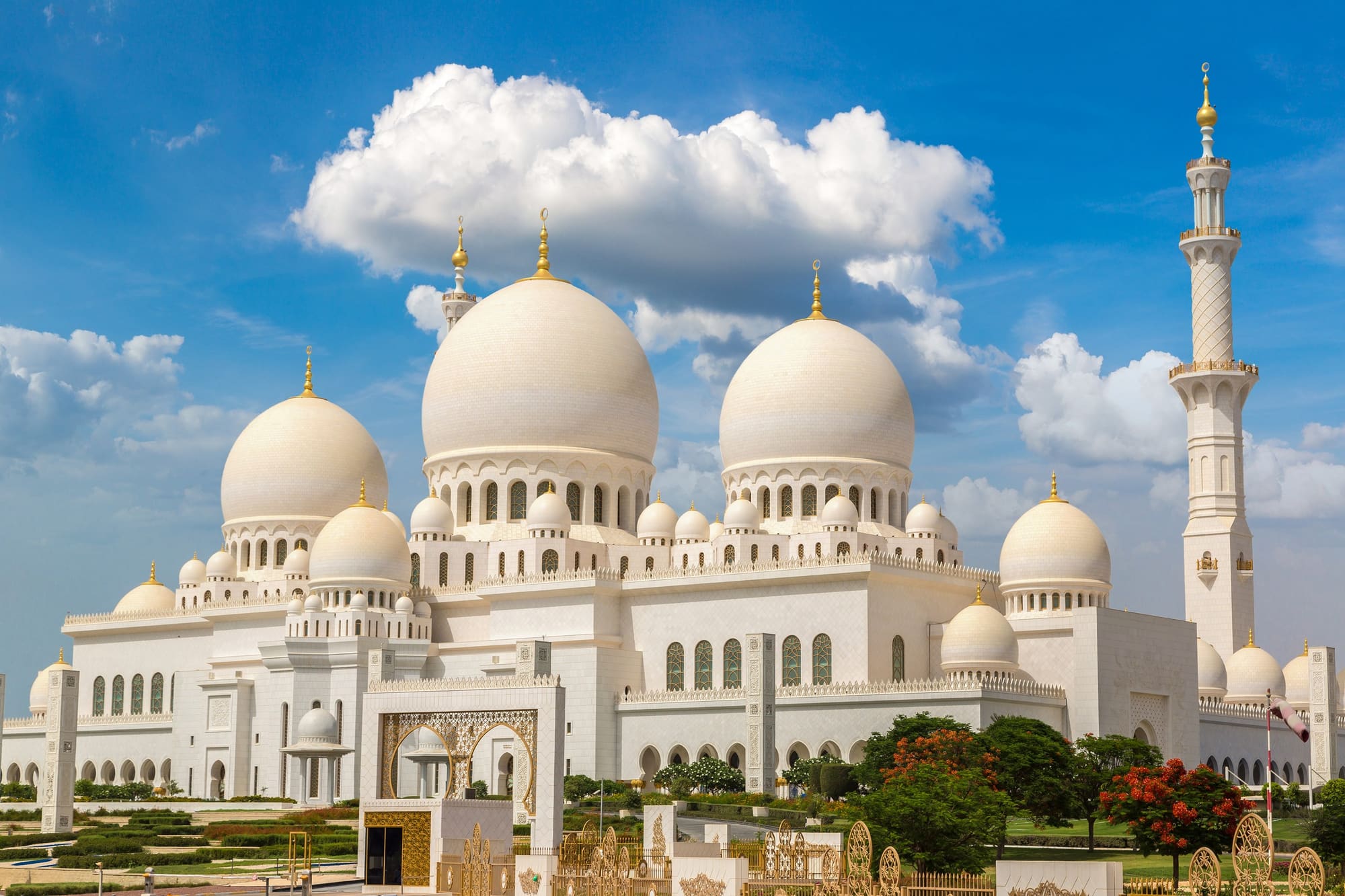 The white marble domes of Sheikh Zayed Grand Mosque against a clear blue sky
